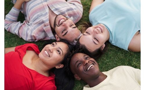 Four teenagers smiling while laying down outdoors