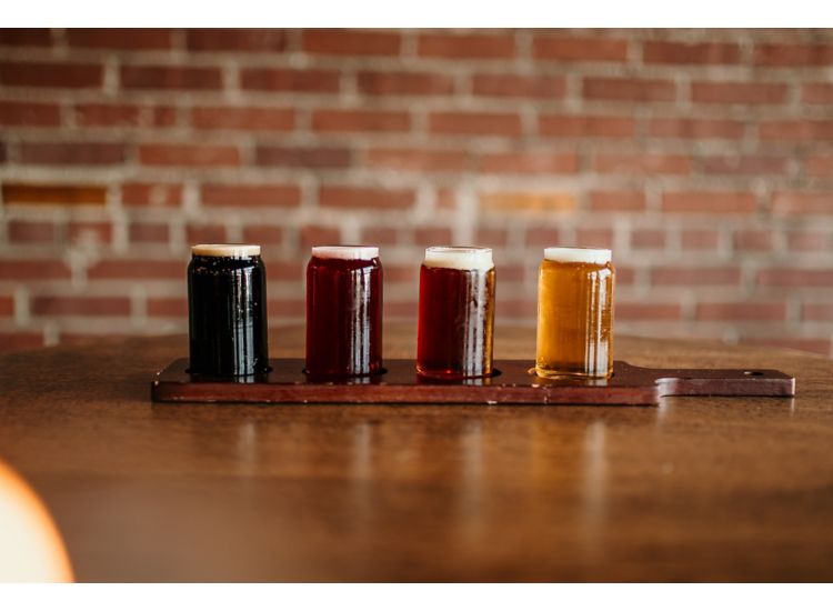 Four beer glasses in a flight sitting on a table.