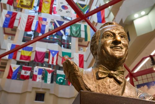 A bronze bust of Danny Thomas in front of a collection of hanging flags.