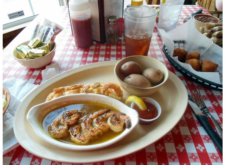 Plate with shrimp and potatoes on a table with a red check cloth.