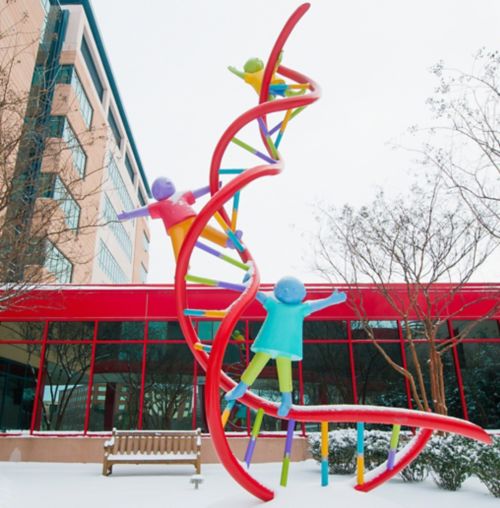 brightly colored sculpture of DNA model with children playing on the double helix in a winter landscape