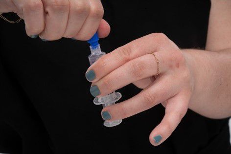 Woman removes cap from heparin syringe