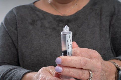 Woman removes air from the saline syringe