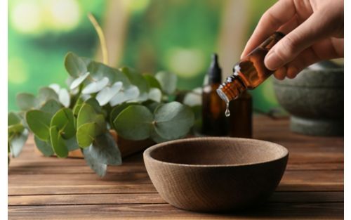 Person pouring bottle of oil into wooden bowl