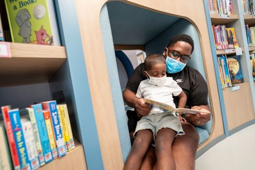 Father holds young son while reading a book together.