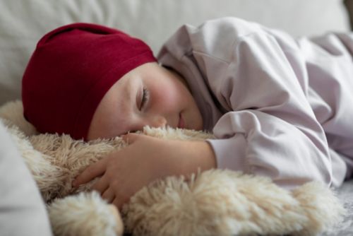 Child cancer patient sleeping with stuffed animal.