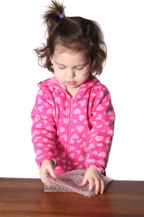 Un enfant jouant avec du papier à bulles.