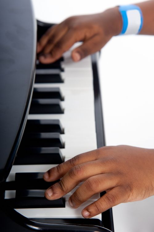 पियानो बजाते हुए बच्चे के हाथों का क्लोज़अप