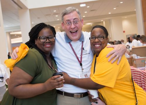 Photo of man with his arms around the shoulders of two women.