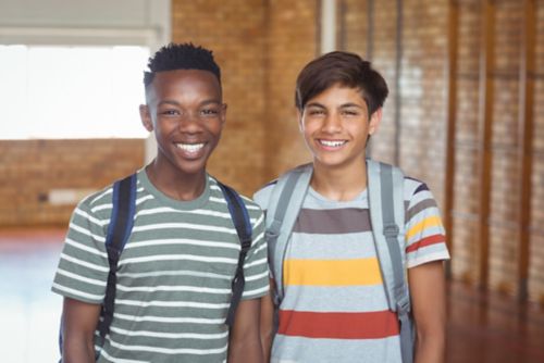 Two teen boys smiling and wearing backpacks