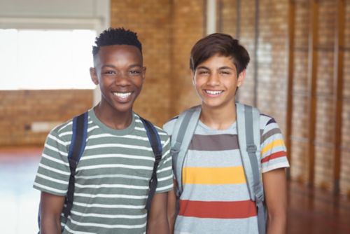 Dos adolescentes sonrientes con mochilas