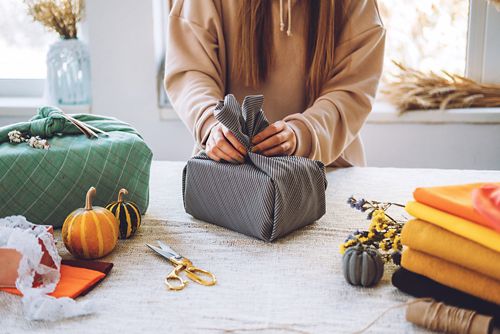 woman wrapping gift in autumn