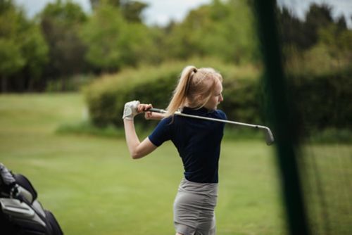 Woman swings golf club