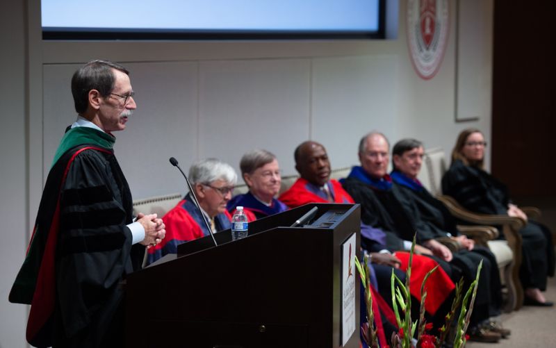 Man at podium, other people sitting to his right