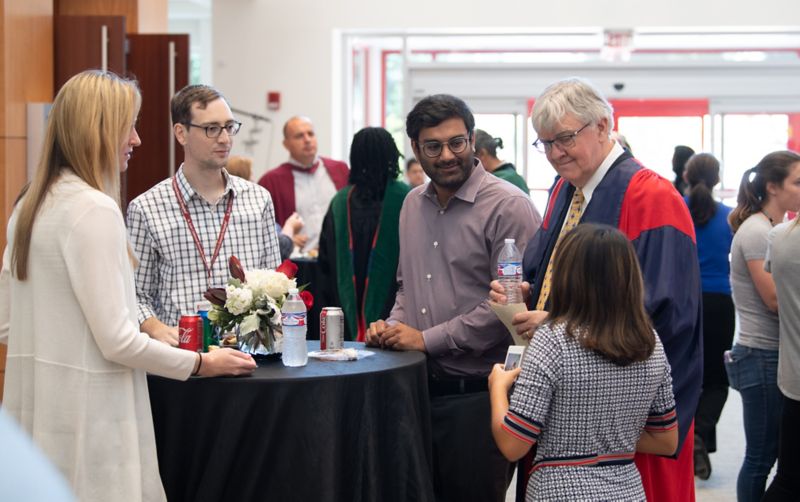 Group of people standing around a high table.