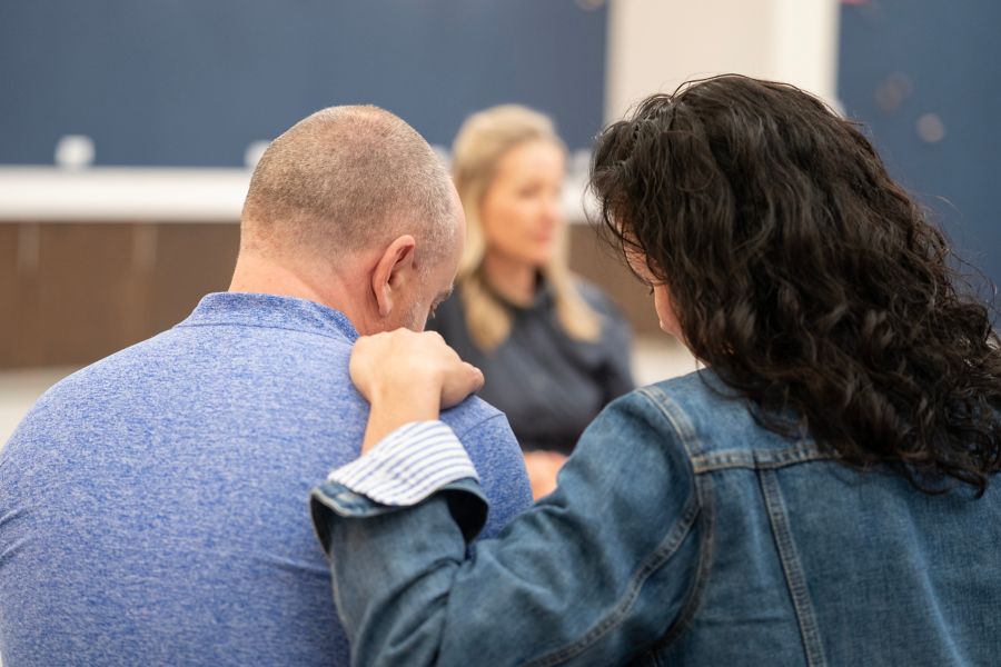 Woman comforting man in group circle setting