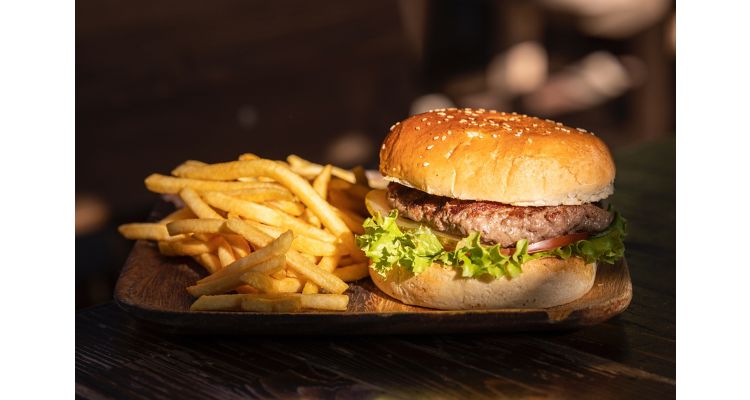 Hamburger and french fries on a wooden plate.