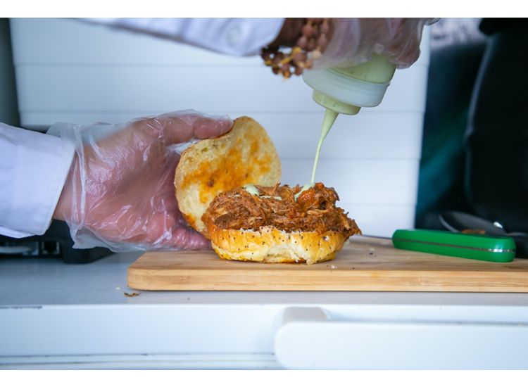 photo of someone saucing a bbq sandwich 