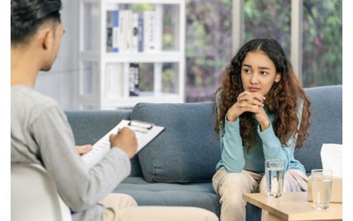 Woman listens to doctor or counselor while sitting on couch