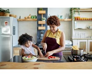 Girl and mother cooking healthy foods in the kitchen together