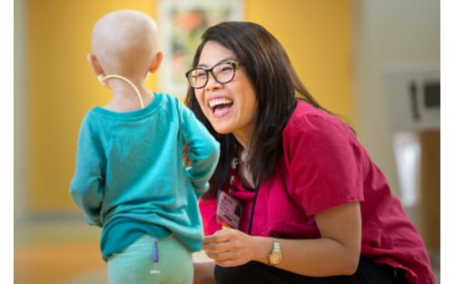 Nurse smiling while talking with small female child patient