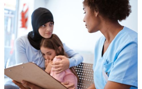 Woman embracing daughter while looking at nurse