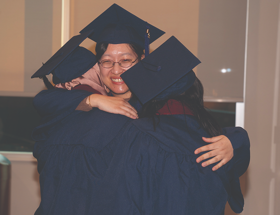 Three graduates hugging at their convocation.