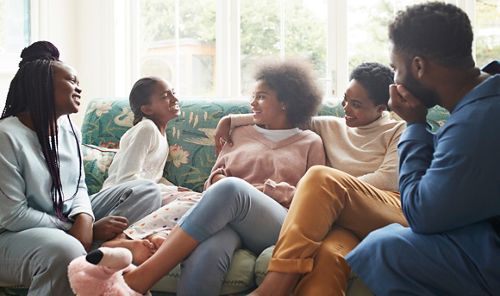 A family in their home talking and laughing together while sitting on a couch.