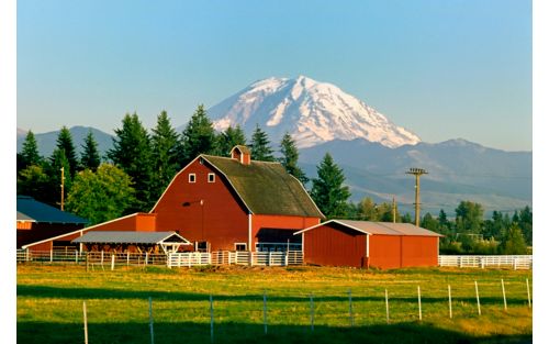 barn in a valley with snowcapped mountains in the distance