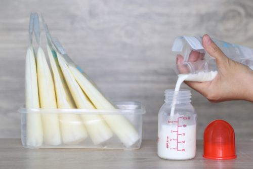 Breastmilk being poured into a bottle.