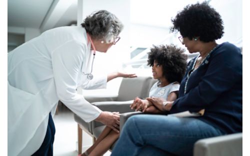 image of woman in white coat greeting child and her mother