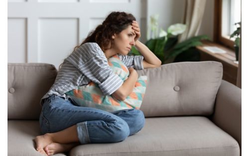 Woman holding head while sitting down