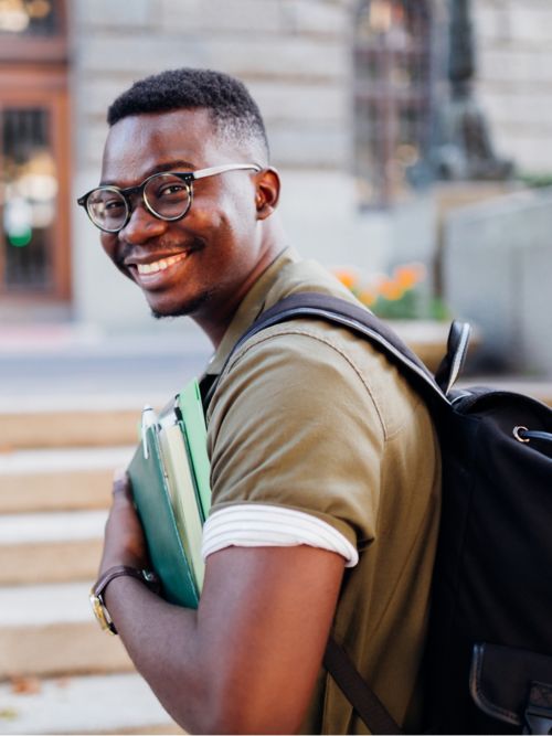 Smiling young man with backpack and books