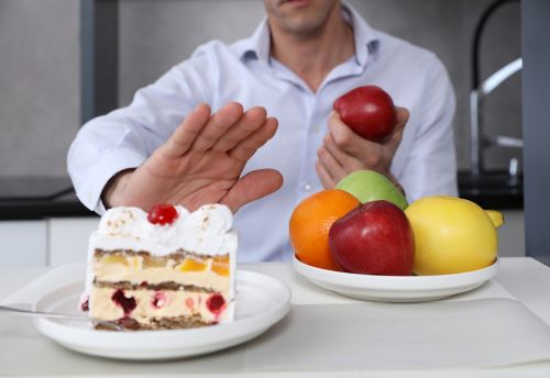 Man holding apple and saying no to cake