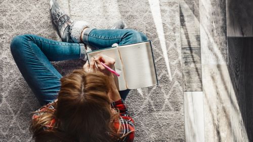 girl sitting on floor writing in journal