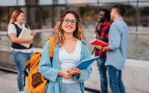 photo of girl standing on sidewalk with group of people in the background