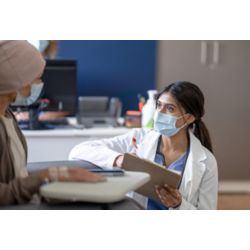 Young female doctor talks with patient in clinical setting