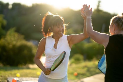 A person holding a tennis racket and giving someone a high five