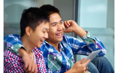 Two males smiling while using cellphone and tablet device