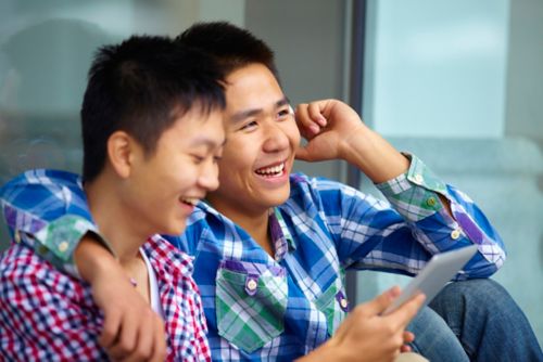 Two males on their cellphones and smiling