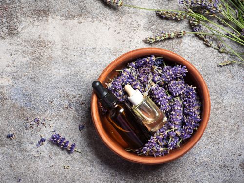 A bowl of lavender with a container of oil