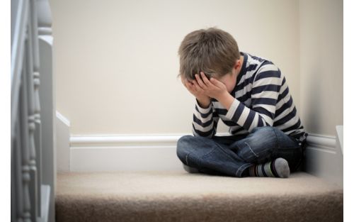 Child crying with his head in his hands 