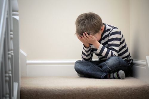 Child crying with his head in his hands