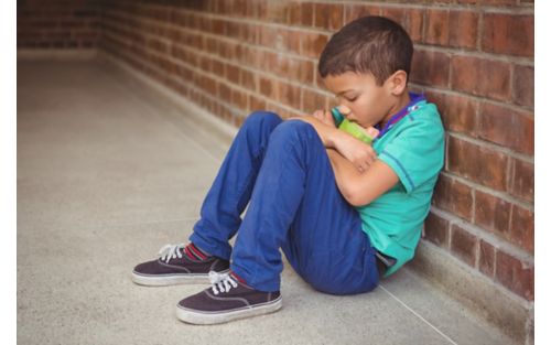 Young male child crouched looking sad