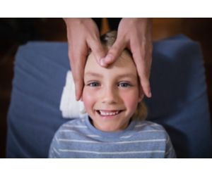 Child smiling while undergoing acupoint therapy