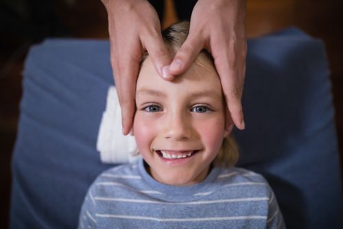 Child smiling while undergoing acupoint therapy