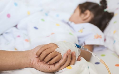 image of child in hospital bed w/parent holding hand