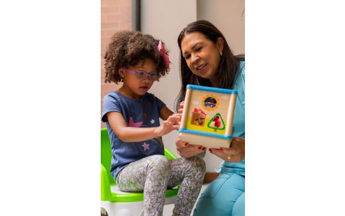 Female child plays with toy with early intervention counselor