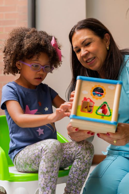 Female child plays with toy with early intervention counselor