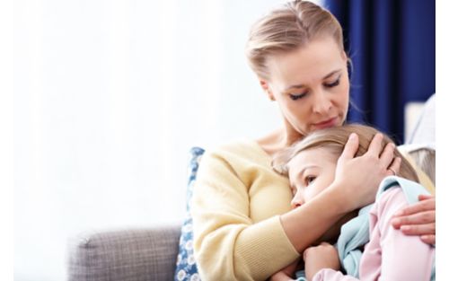 Mother hugging child on couch